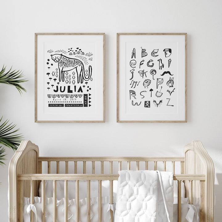 Nursery with wooden crib and a birth print and animal alphabet print hang above in wooden frames.