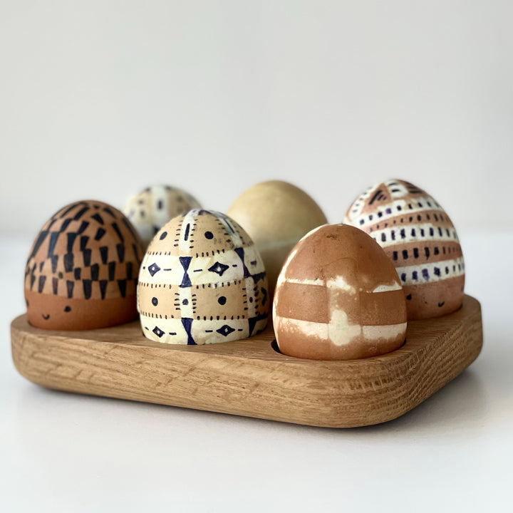A wooden egg holder with six beautiful dyed eggs in natural brown tones from onion skin.