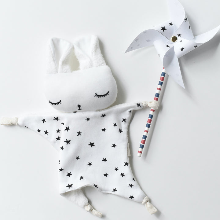 Cotton soft Cuddle Bunny posed holding a star themed paper pinwheel.