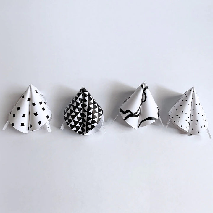 Four cookie shaped paper fortunes in different black and white patterns.