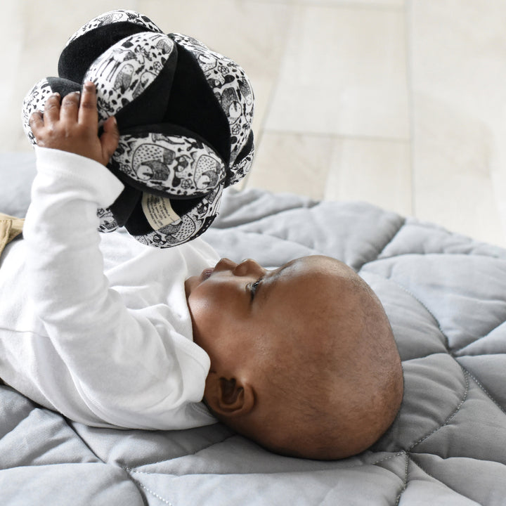 Baby holding and looking at nordic montessori clutch ball.